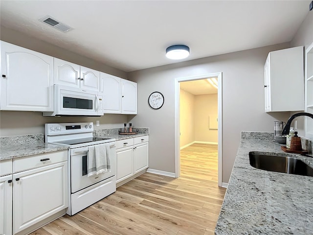 kitchen with white cabinetry, sink, white appliances, and light stone countertops