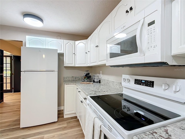 kitchen with light wood-type flooring, white cabinets, white appliances, light stone counters, and a textured ceiling