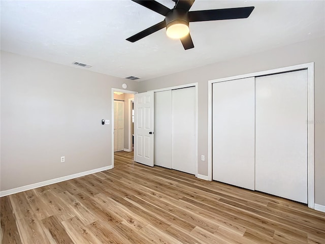 unfurnished bedroom with multiple closets, light hardwood / wood-style flooring, and ceiling fan