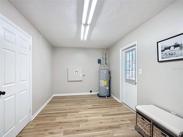 clothes washing area featuring light hardwood / wood-style floors and electric water heater