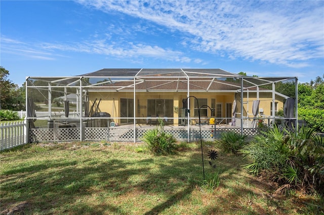 back of property with a patio, glass enclosure, and a lawn