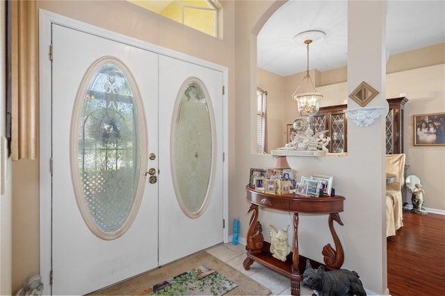 entrance foyer featuring french doors, a notable chandelier, a healthy amount of sunlight, and light hardwood / wood-style flooring