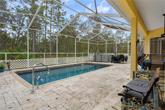 view of swimming pool featuring a hot tub, a patio area, and a lanai