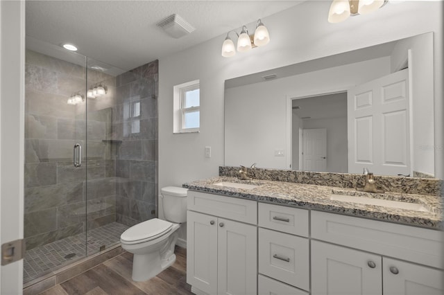 bathroom featuring toilet, an enclosed shower, a textured ceiling, vanity, and hardwood / wood-style flooring