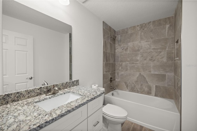 full bathroom with tiled shower / bath combo, vanity, hardwood / wood-style flooring, toilet, and a textured ceiling