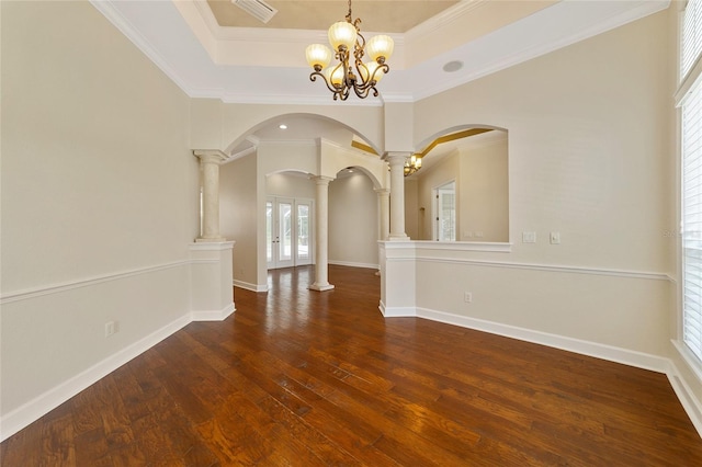 empty room featuring an inviting chandelier, dark hardwood / wood-style floors, crown molding, and decorative columns