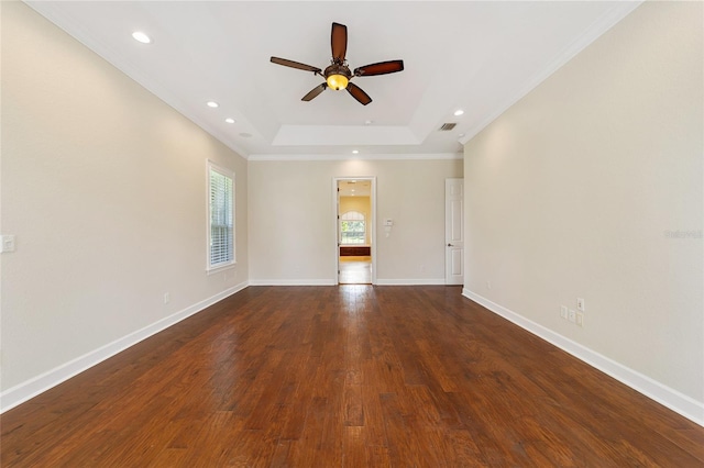 empty room with ceiling fan, a raised ceiling, dark hardwood / wood-style floors, and crown molding