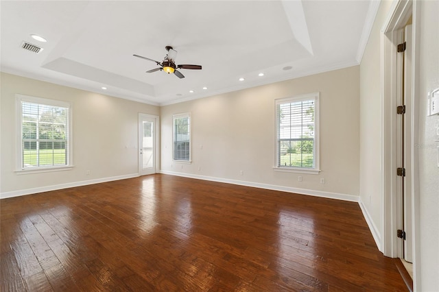 spare room featuring ceiling fan, a tray ceiling, dark hardwood / wood-style floors, and a wealth of natural light