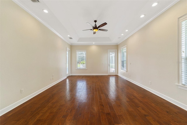 empty room featuring ceiling fan, a raised ceiling, dark hardwood / wood-style floors, and crown molding