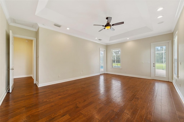 empty room with ceiling fan, ornamental molding, a tray ceiling, and dark hardwood / wood-style flooring