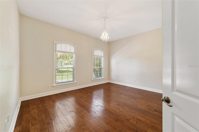 spare room featuring a notable chandelier and dark hardwood / wood-style flooring