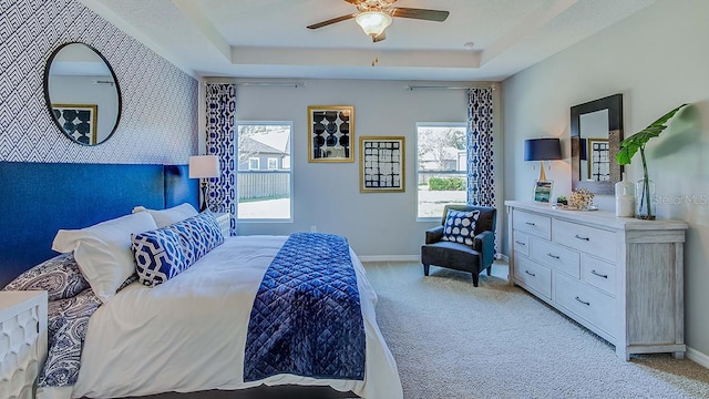 bedroom featuring a tray ceiling, ceiling fan, and light colored carpet