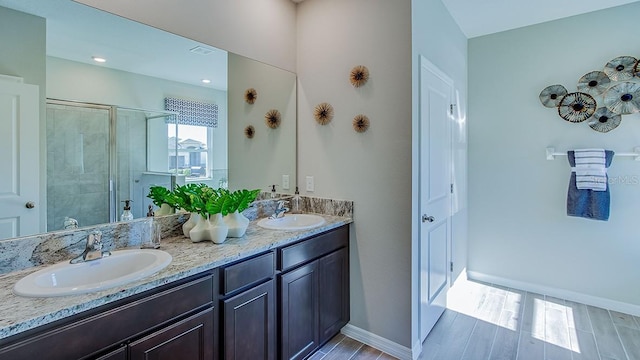 bathroom with wood-type flooring, vanity, and a shower with shower door