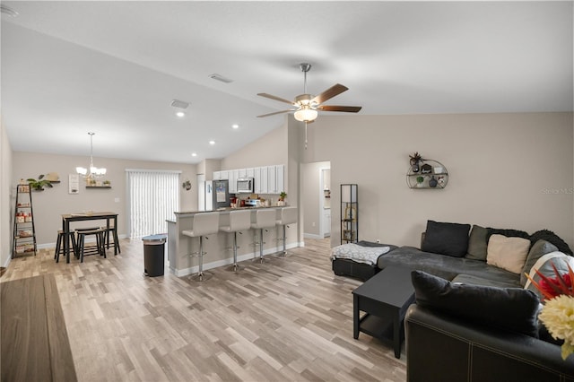 living room with ceiling fan with notable chandelier, light wood-type flooring, and vaulted ceiling