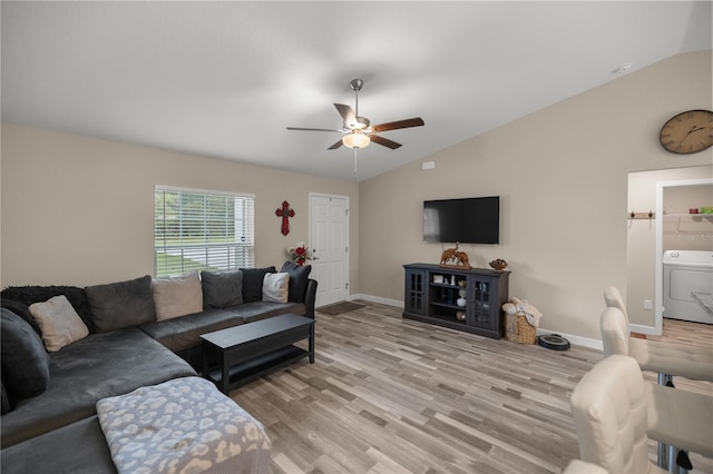 living room with ceiling fan, vaulted ceiling, washer / clothes dryer, and light hardwood / wood-style flooring