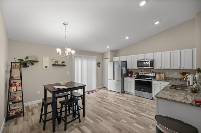 kitchen with sink, light hardwood / wood-style floors, white cabinetry, vaulted ceiling, and appliances with stainless steel finishes