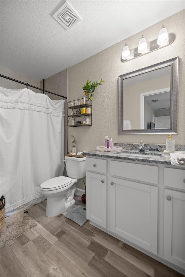 bathroom with vanity, a textured ceiling, hardwood / wood-style flooring, toilet, and a shower with shower curtain