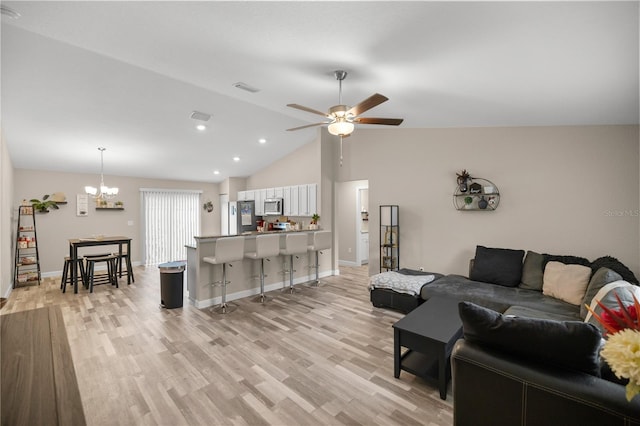 living room featuring ceiling fan with notable chandelier, lofted ceiling, and light hardwood / wood-style floors