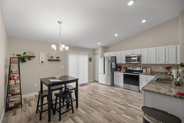 kitchen featuring white cabinetry, sink, hanging light fixtures, light stone counters, and stainless steel appliances