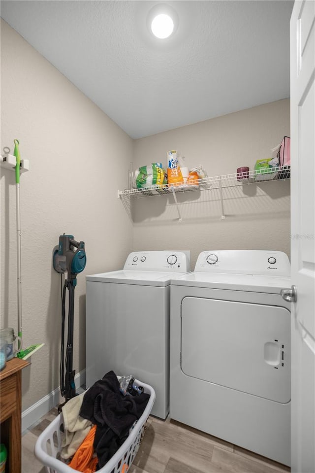 laundry room with washing machine and clothes dryer, light hardwood / wood-style floors, and a textured ceiling