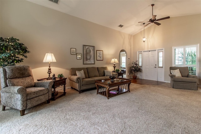 carpeted living room with ceiling fan and high vaulted ceiling