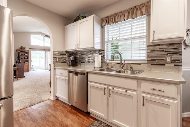 kitchen featuring stainless steel appliances, light hardwood / wood-style flooring, decorative backsplash, and sink