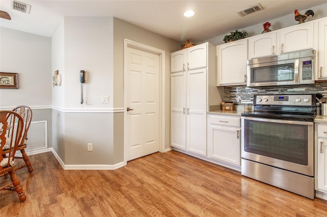 kitchen with appliances with stainless steel finishes, light hardwood / wood-style floors, decorative backsplash, and white cabinetry