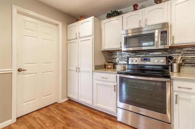 kitchen featuring backsplash, white cabinets, appliances with stainless steel finishes, and light wood-type flooring