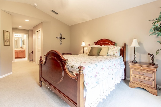 bedroom with light carpet, vaulted ceiling, and ensuite bathroom