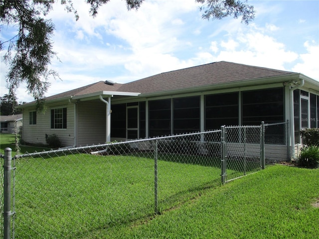 rear view of house with a lawn, fence, and a sunroom