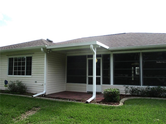 exterior space with a yard, a shingled roof, and a patio