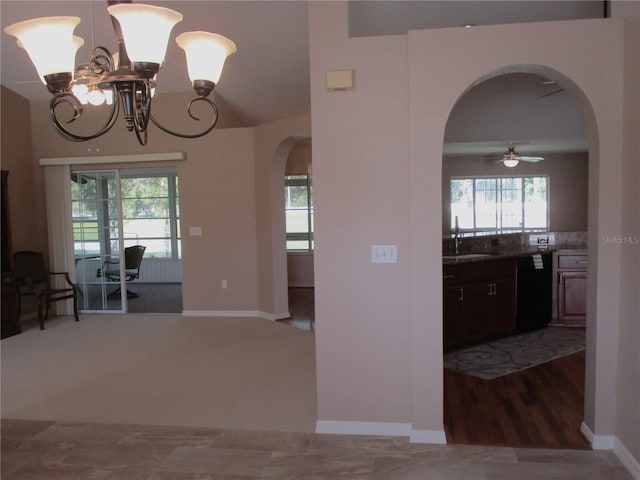 interior space with arched walkways, vaulted ceiling, a sink, wood finished floors, and baseboards