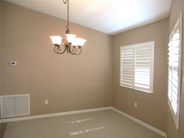 spare room featuring baseboards, visible vents, and a chandelier