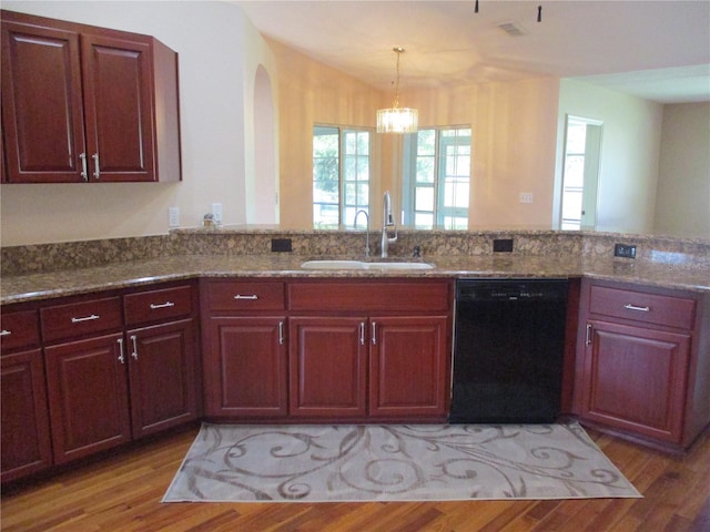 kitchen with dark stone countertops, light wood-type flooring, dishwasher, and a sink