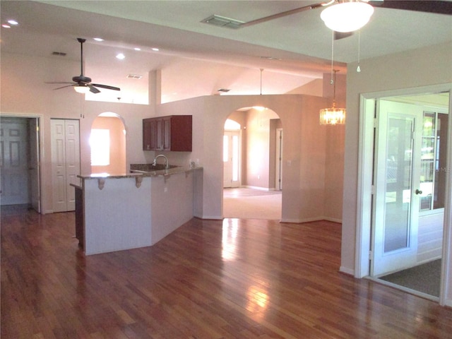 kitchen featuring arched walkways, a peninsula, vaulted ceiling, and visible vents