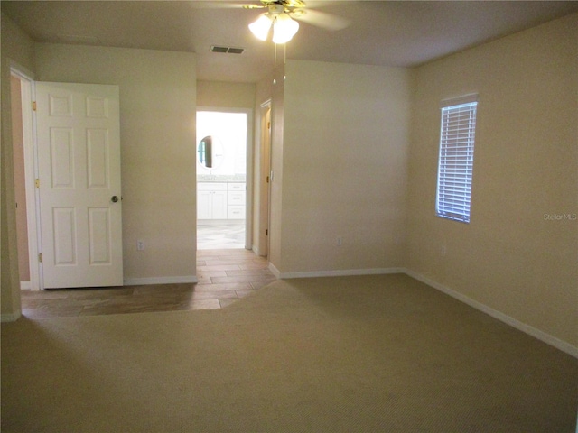 unfurnished room featuring a ceiling fan, wood finished floors, visible vents, and baseboards