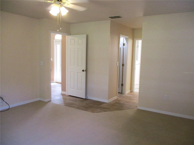 spare room featuring baseboards, visible vents, and light colored carpet