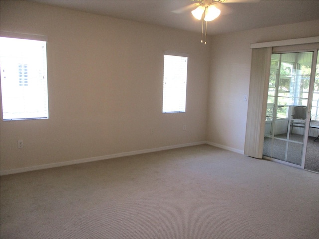 unfurnished room featuring a healthy amount of sunlight, ceiling fan, light carpet, and baseboards