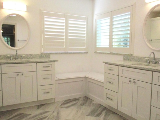 full bath with marble finish floor, two vanities, and a sink