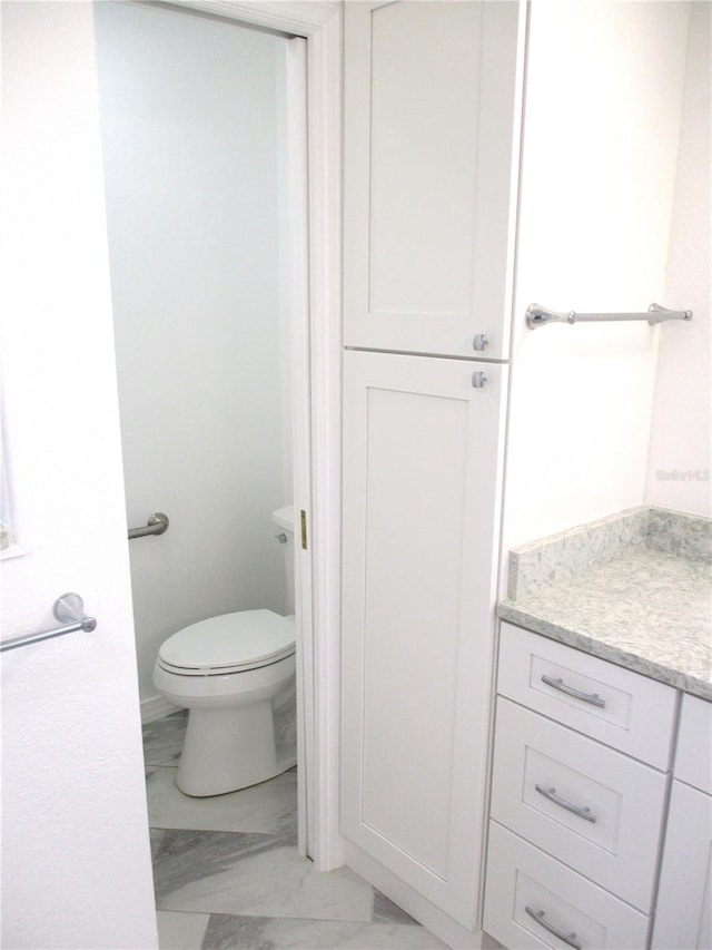 bathroom with toilet, marble finish floor, and vanity