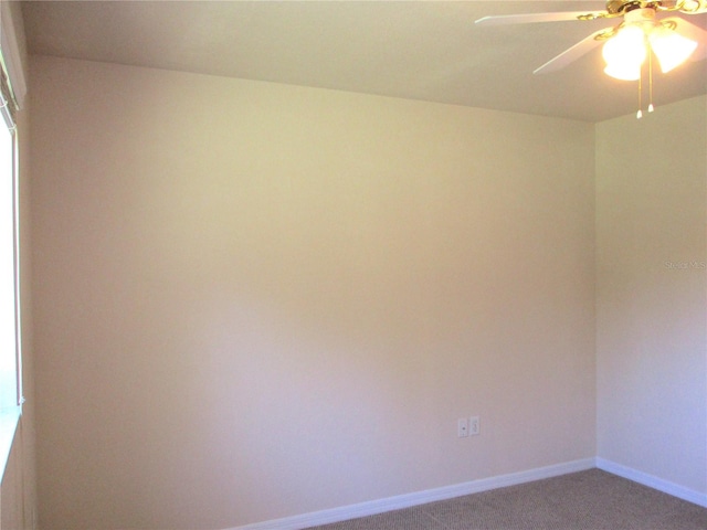 carpeted spare room featuring ceiling fan and baseboards