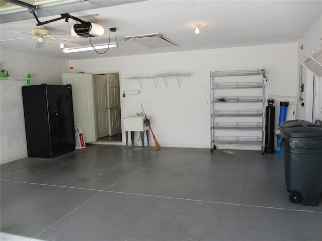 garage featuring black refrigerator with ice dispenser and a garage door opener