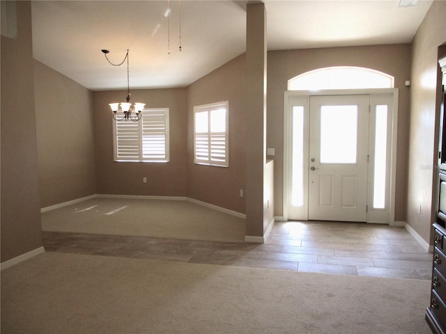 carpeted foyer entrance featuring baseboards, lofted ceiling, and a notable chandelier