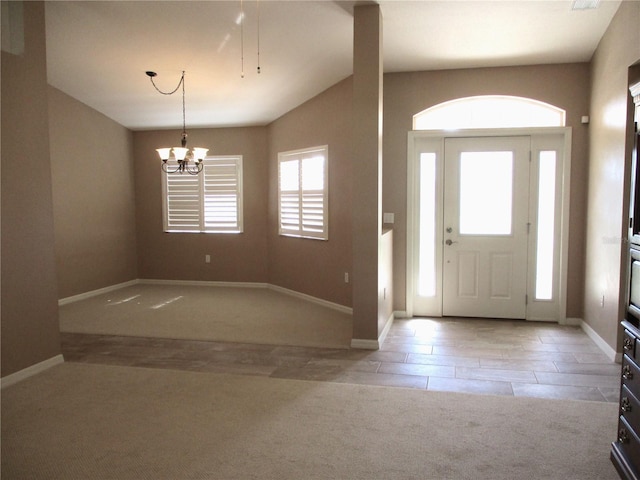 carpeted foyer featuring baseboards, a healthy amount of sunlight, and a chandelier
