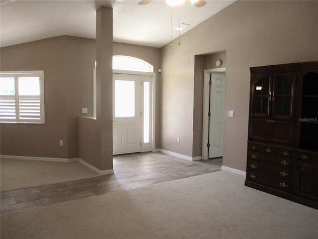 foyer with lofted ceiling, light carpet, ceiling fan, and baseboards