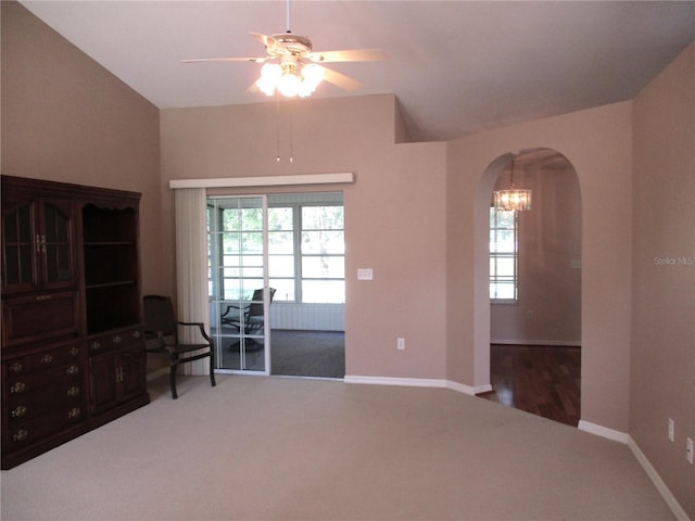 living area featuring arched walkways, carpet flooring, baseboards, and ceiling fan with notable chandelier