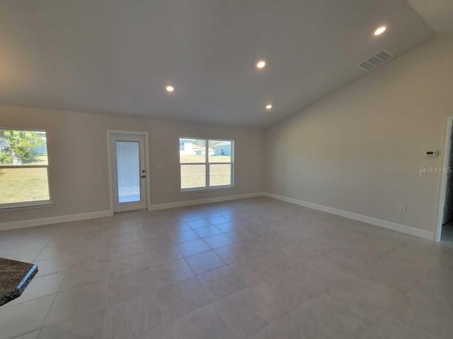 tiled empty room featuring lofted ceiling