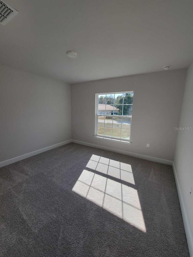 spare room featuring dark colored carpet