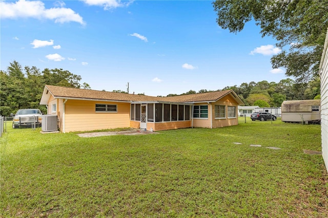 rear view of property featuring central AC unit, a sunroom, and a lawn