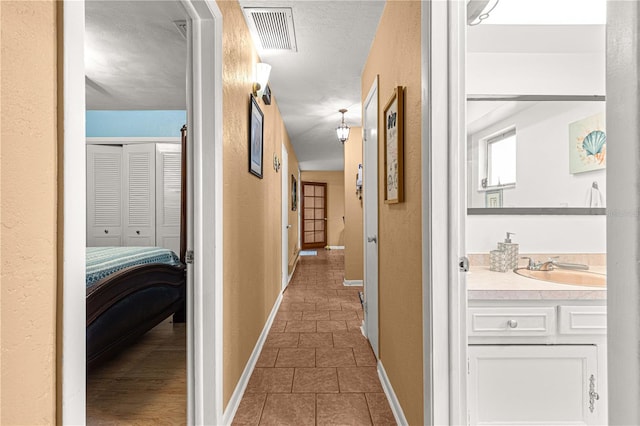 corridor featuring dark tile patterned flooring and sink